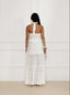 Woman wearing a white broderie anglaise dress against a white background